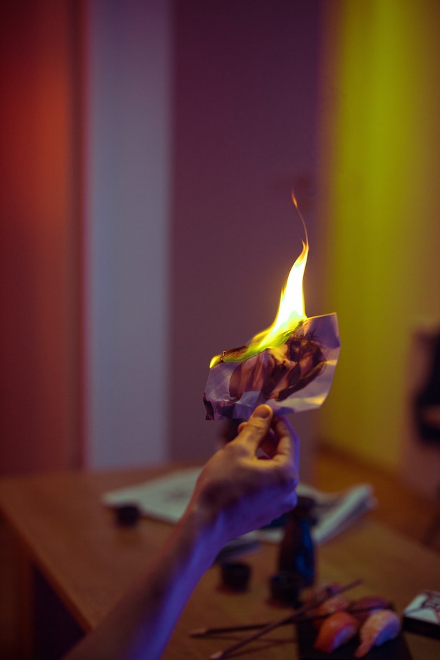Photo of a hand holding a burning photo