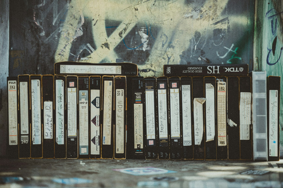 Row of VHS taps next to wall covered in graffiti