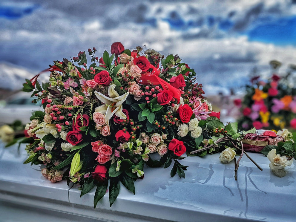 Flowers on a casket at an outdoor funeral service.  