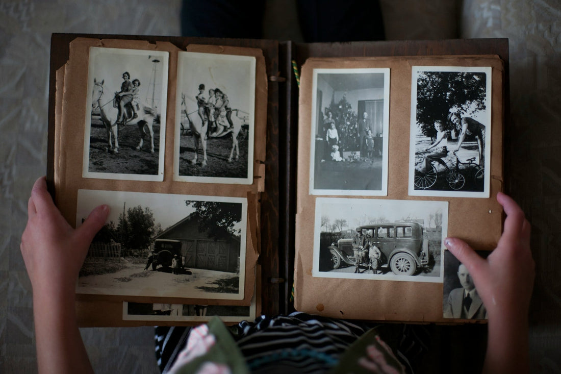 Person opening photo album displaying grayscale photos.