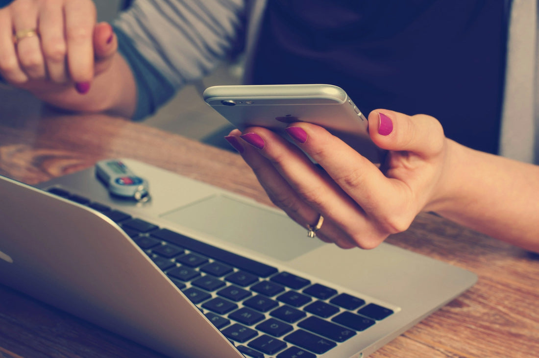 Woman backing up photos on her phone and computer. 