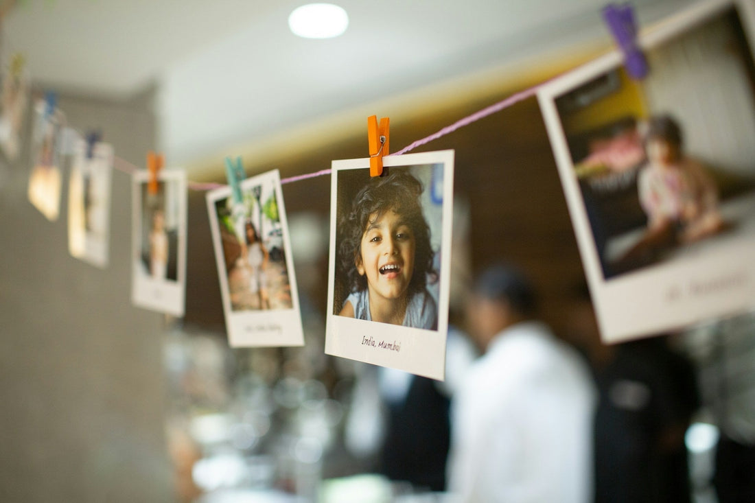 String with clipped pictures and woman in white long-sleeve shirt holding printer paper.